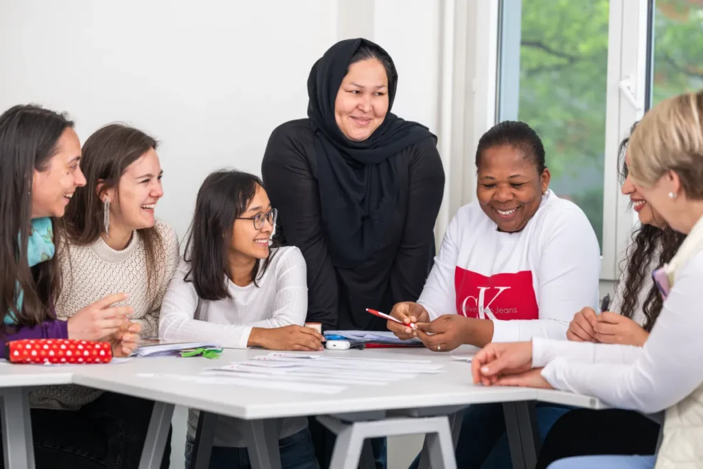 Mehrere Frauen die an einem Tisch sind und Deutsch lernen.